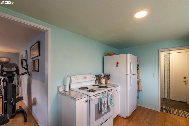 kitchen with white appliances, light countertops, light wood finished floors, and white cabinets