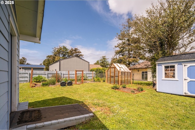 view of yard with a greenhouse, an outdoor structure, a shed, and a vegetable garden