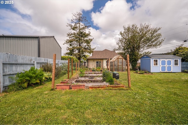 view of yard with a vegetable garden, an outbuilding, a greenhouse, and a storage shed