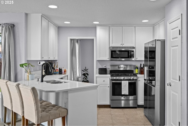 42015 NW Buckshire St, Banks, OR 97106 - kitchen featuring a peninsula, white cabinets, a sink, appliances with stainless steel finishes, and light tile patterned floors