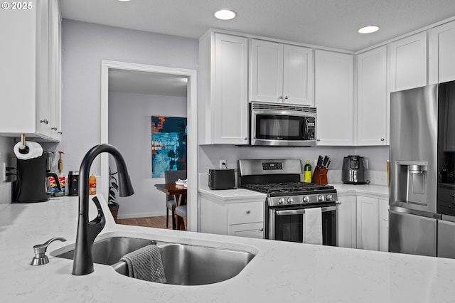 42015 NW Buckshire St, Banks, OR 97106 - kitchen featuring stainless steel appliances, light stone counters, white cabinetry, and a sink