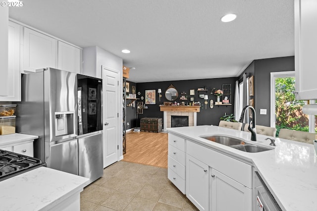42015 NW Buckshire St, Banks, OR 97106 - kitchen featuring a sink, stainless steel fridge with ice dispenser, a tiled fireplace, and white cabinets