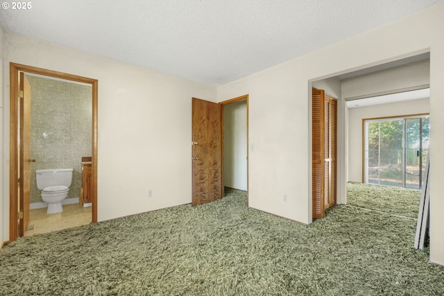 unfurnished bedroom featuring light carpet, ensuite bath, a closet, and a textured ceiling