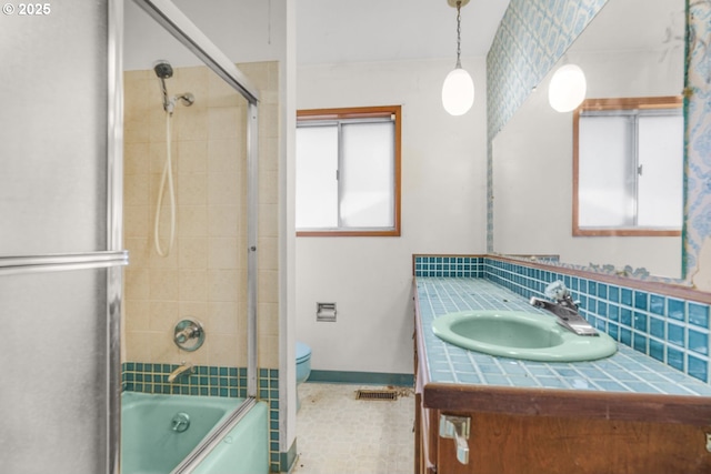 full bathroom with enclosed tub / shower combo, a wealth of natural light, vanity, and toilet