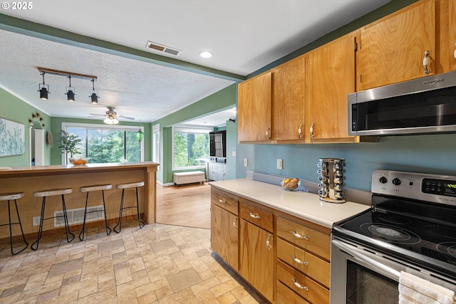 9333 SW 4th Ave, Portland, OR 97219 - kitchen with appliances with stainless steel finishes, light countertops, ceiling fan, rail lighting, and brown cabinets