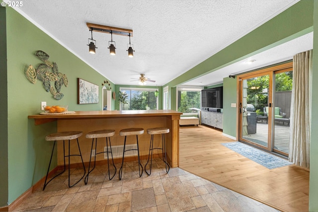 9333 SW 4th Ave, Portland, OR 97219 - bar area featuring a textured ceiling, healthy amount of natural light, a ceiling fan, baseboards, and stone tile floors