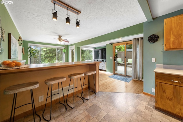 9333 SW 4th Ave, Portland, OR 97219 - kitchen with plenty of natural light, a breakfast bar area, baseboards, stone tile floors, and a textured ceiling