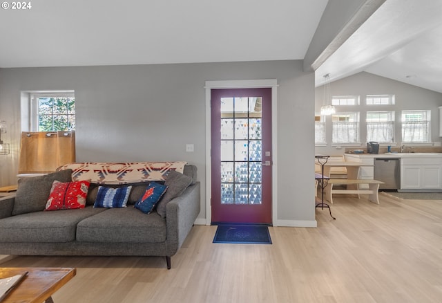 living room featuring lofted ceiling, light wood-style flooring, and baseboards