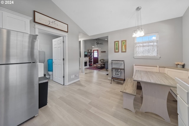 kitchen featuring pendant lighting, freestanding refrigerator, white cabinets, vaulted ceiling, and light wood-type flooring