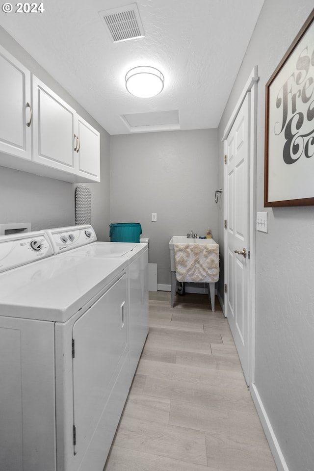 laundry area with separate washer and dryer, visible vents, baseboards, light wood-type flooring, and cabinet space