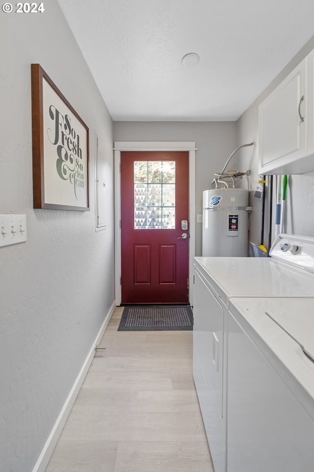 washroom with cabinet space, baseboards, a textured wall, electric water heater, and washing machine and dryer