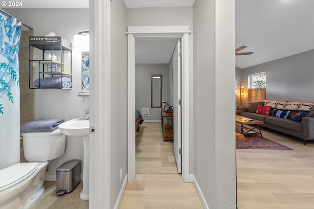 ensuite bathroom featuring connected bathroom, toilet, wood finished floors, a ceiling fan, and baseboards