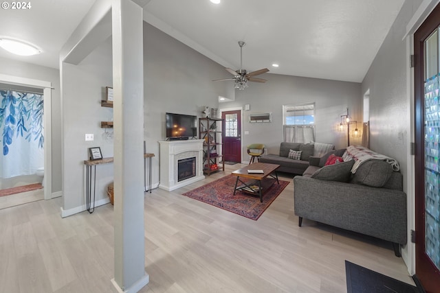 living area with baseboards, a ceiling fan, lofted ceiling, light wood-style floors, and a fireplace