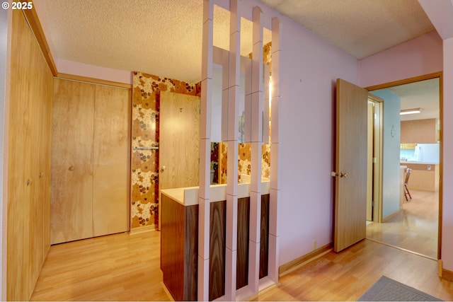 corridor with a textured ceiling and wood finished floors