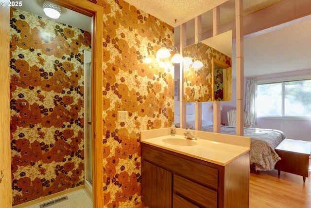 ensuite bathroom with wallpapered walls, visible vents, ensuite bathroom, a textured ceiling, and vanity