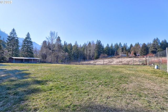 view of yard with fence and a rural view