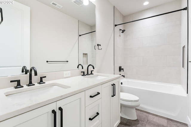 full bathroom with tiled shower / bath, vanity, and toilet