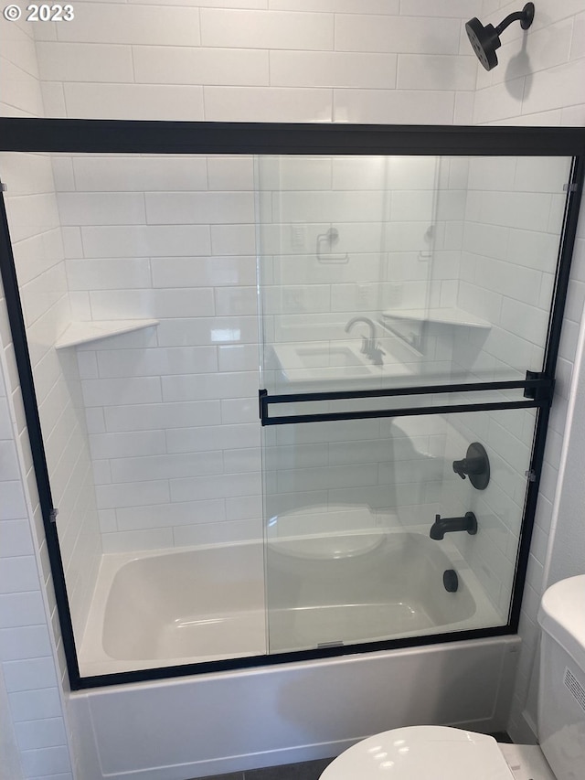 bathroom with toilet and shower / bath combination with glass door