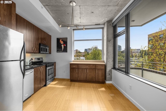 1234 SW 18th Ave Unit 305, Portland, OR 97205 - kitchen with dark brown cabinets, baseboards, light wood-style flooring, appliances with stainless steel finishes, and a view of city