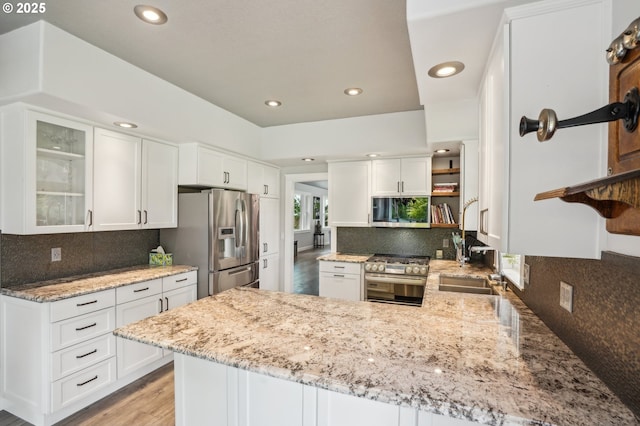 12875 Peggys Pl, Hubbard, OR 97032 - kitchen with open shelves, a peninsula, white cabinets, light stone counters, and appliances with stainless steel finishes