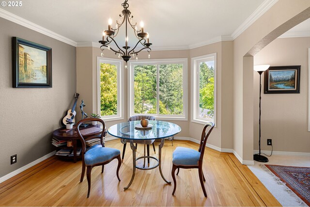 dining area with a notable chandelier, arched walkways, baseboards, light wood-type flooring, and ornamental molding