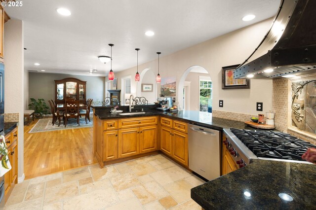 kitchen with a sink, ventilation hood, arched walkways, recessed lighting, and stainless steel dishwasher