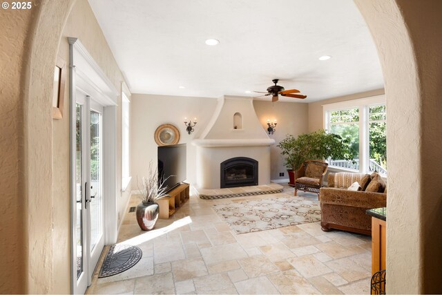 living area with stone tile floors, a ceiling fan, recessed lighting, and a fireplace