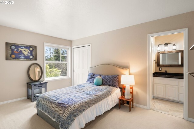 bedroom with baseboards, a sink, and light carpet