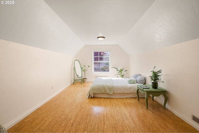bedroom with baseboards, vaulted ceiling, and light colored carpet