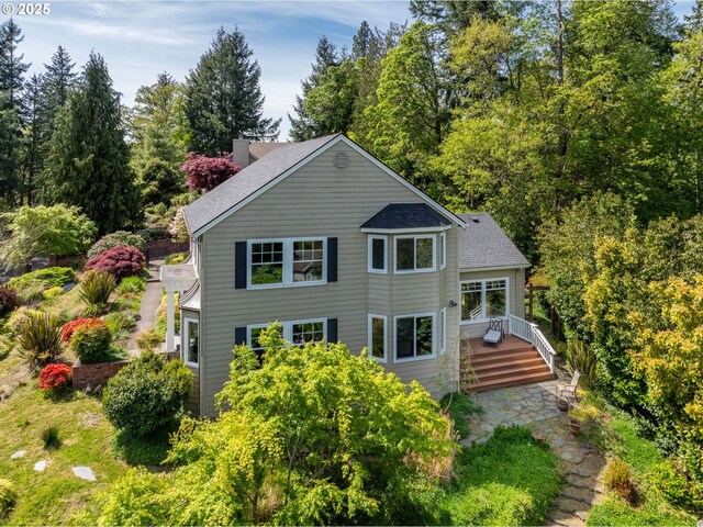 back of house with a shingled roof, a wooden deck, and a chimney