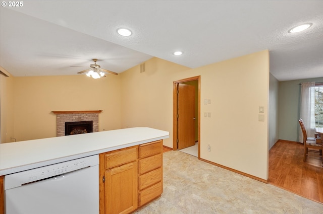 kitchen featuring light hardwood / wood-style flooring, a textured ceiling, white dishwasher, ceiling fan, and a fireplace