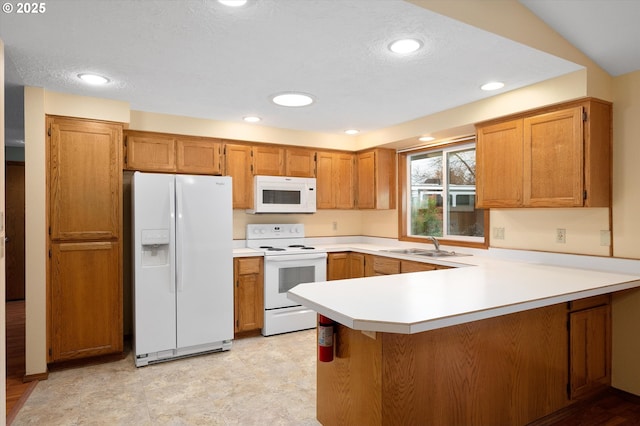 kitchen with sink, white appliances, kitchen peninsula, and a textured ceiling