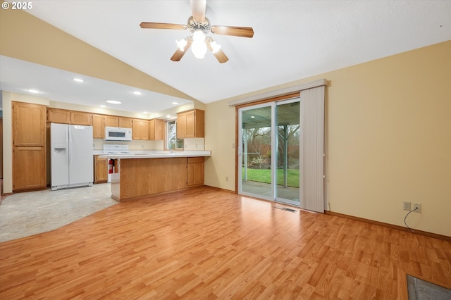 kitchen with lofted ceiling, white appliances, ceiling fan, kitchen peninsula, and light wood-type flooring