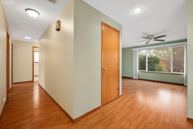 corridor featuring light hardwood / wood-style flooring and a textured ceiling