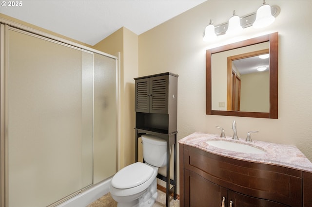 bathroom featuring vanity, a shower with shower door, and toilet