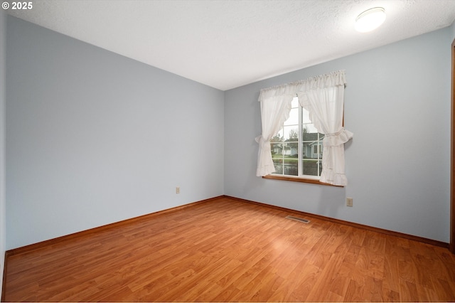 spare room featuring hardwood / wood-style flooring and a textured ceiling