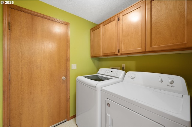 washroom with cabinets, washer and dryer, and a textured ceiling