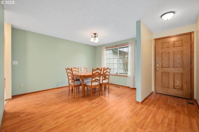 dining area with a textured ceiling and light wood-type flooring