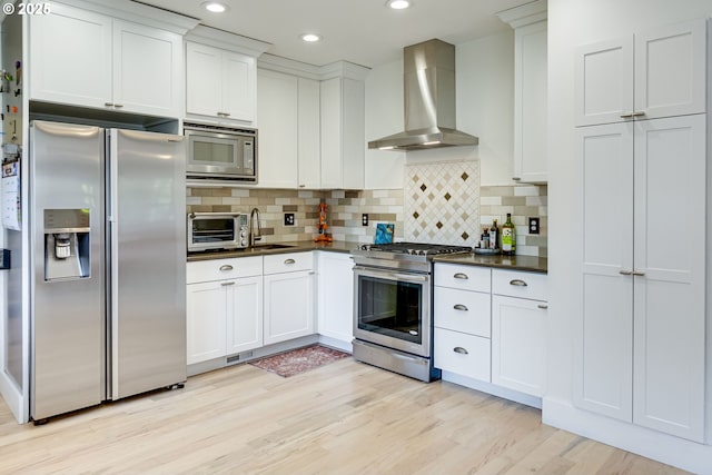 kitchen with dark countertops, a toaster, wall chimney range hood, and stainless steel appliances