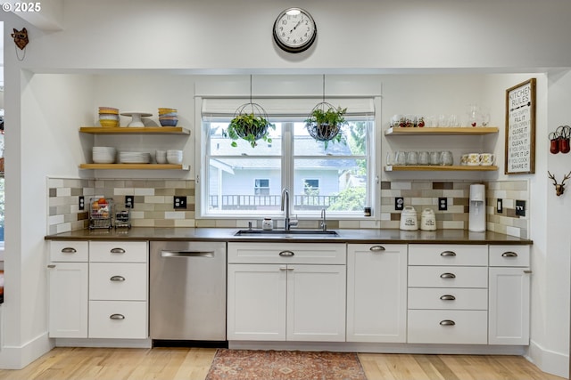 kitchen with open shelves, dark countertops, a sink, and dishwasher