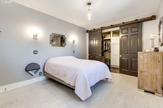bedroom featuring baseboards, light wood-style flooring, a closet, and a barn door