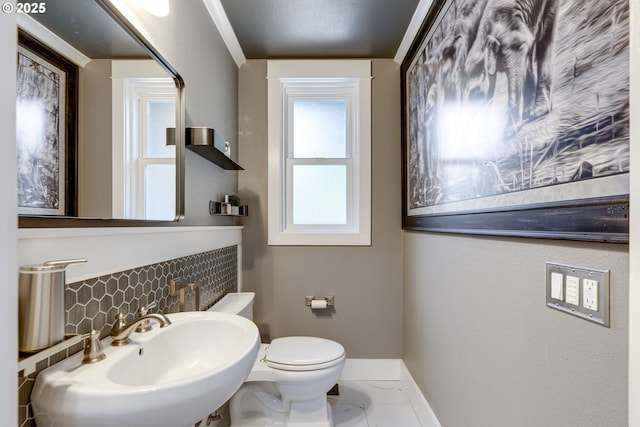 bathroom featuring tasteful backsplash, a sink, baseboards, toilet, and marble finish floor