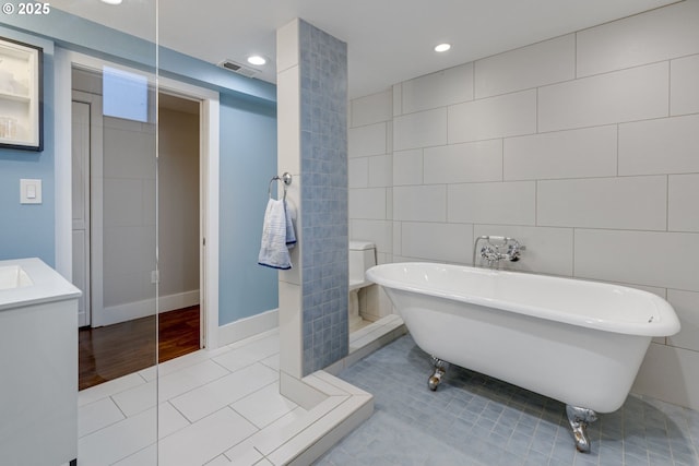 full bathroom featuring tile patterned floors, recessed lighting, tile walls, visible vents, and a soaking tub