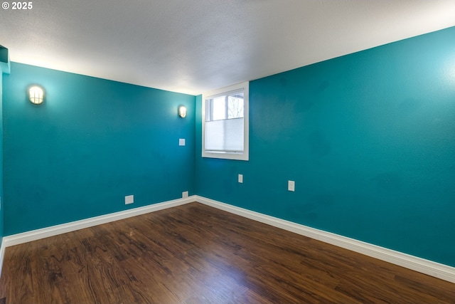 unfurnished room featuring baseboards and dark wood finished floors