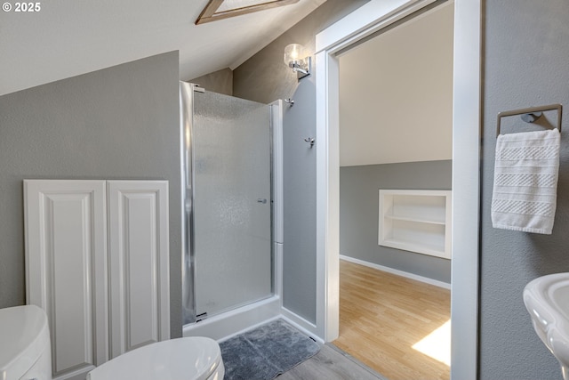 bathroom with wood finished floors, built in shelves, a stall shower, and toilet