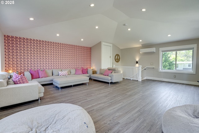 living area with baseboards, a wall mounted AC, vaulted ceiling, and wood finished floors