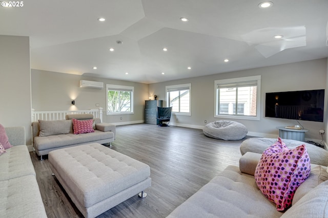 living room with an AC wall unit, recessed lighting, baseboards, and wood finished floors