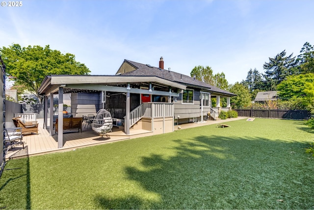 back of house featuring fence, a wooden deck, a chimney, and a yard