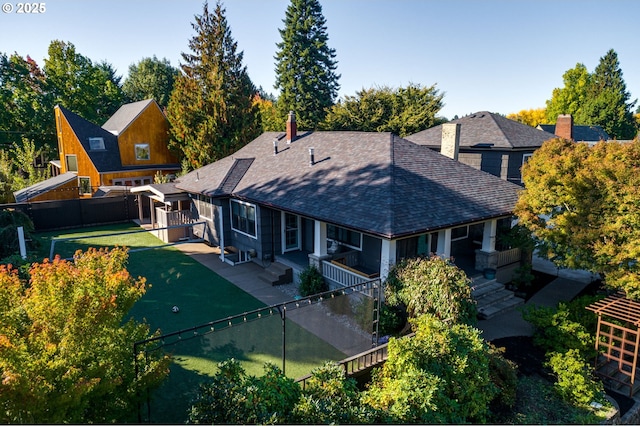 rear view of house with a lawn, a fenced backyard, stairs, and a shingled roof