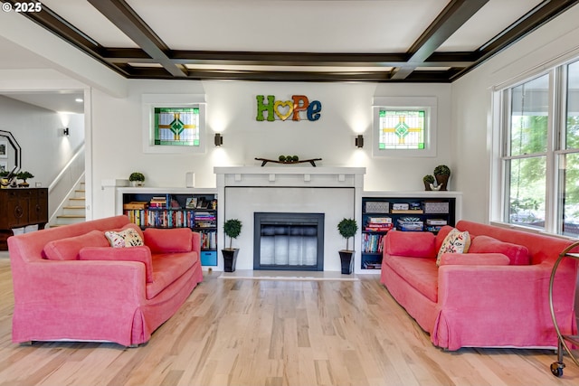 living area with stairs, a fireplace with flush hearth, wood finished floors, and coffered ceiling